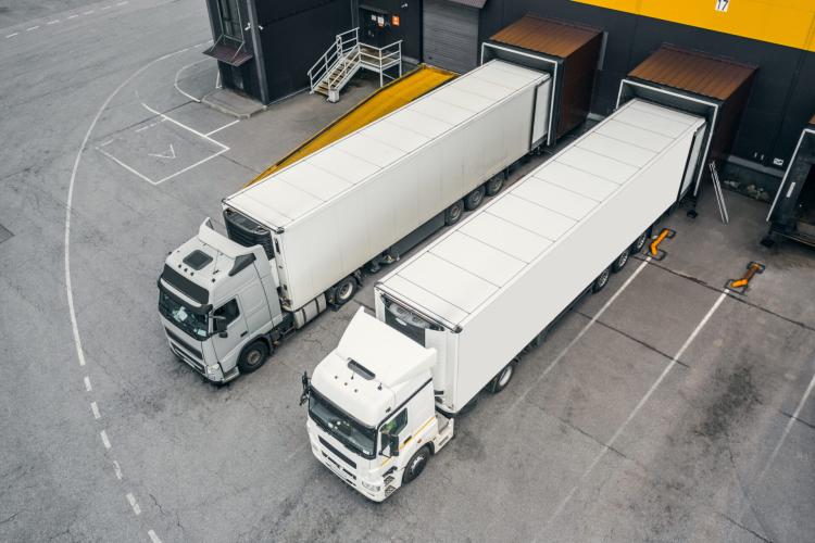 two white trucks during loading at the dates of a warehouse